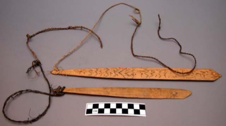 The Massim pair: two corded blades, the upper carved with chevron bands.