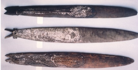 Three of the eleven engraved blades in the Issoudun lot, each head carved differently.