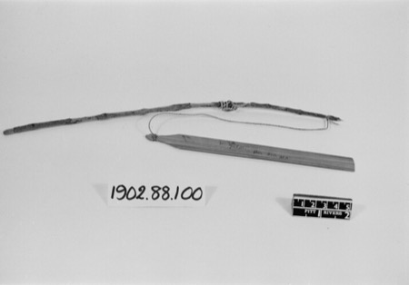 A Minangkabau gasiang tangkurak — a thin incised wooden blade tied by a long cord to a forked stick handle — the West Sumatran spinning...