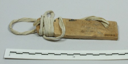 An Arab bull-roarer, a wood board bound at one end with strips of cloth cord; the Lamba lendya, made from the bulb of a gladiolus plant twirled...
