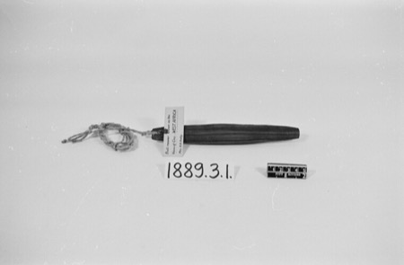 A plain wooden bull-roarer, tapered at both ends with a braided cord tied through one end and labelled simply "West Africa" — shown for the...