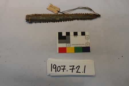 A bone bullroarer with sawtooth edges and a hide cord, shown here for its general Inuit/Arctic form — not the poplar board fastened to a long...