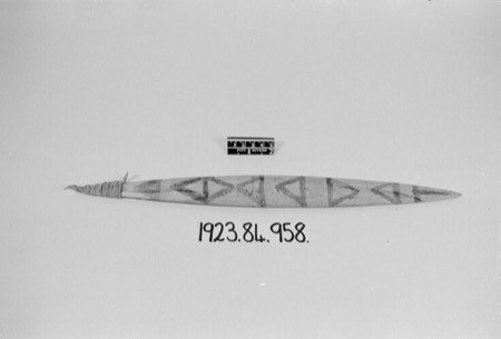 A slender, sharply pointed blade painted down its length with a row of linked triangle outlines, cord wound around its tapered tip,...