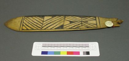 The sibling fish-blade: black chevrons on pale wood, its string knotted through the pointed tail (PRM 1960.6.21.2).