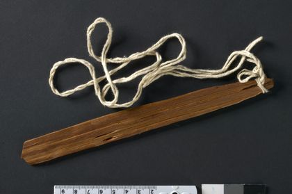 The second Mesbilja whirler, UEM41249/a: a plain tapered slat on its long cotton cord.