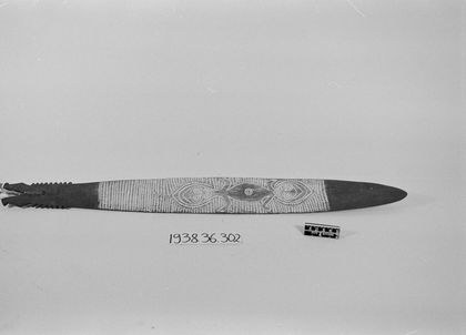 Third of the trio: two round-faced figures flank a central eye, the butt cut into gripping teeth (PRM 1938.36.302).
