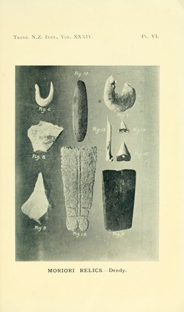 Dendy’s plate of Moriori relics, with the broad carved bullroarer labeled fig. 12 near the lower center among several other objects.