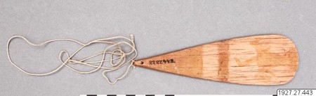 Río Sambú Chocó bullroarer: a pale wooden blade with a narrow neck and broad rounded end beside its loosely coiled cord.