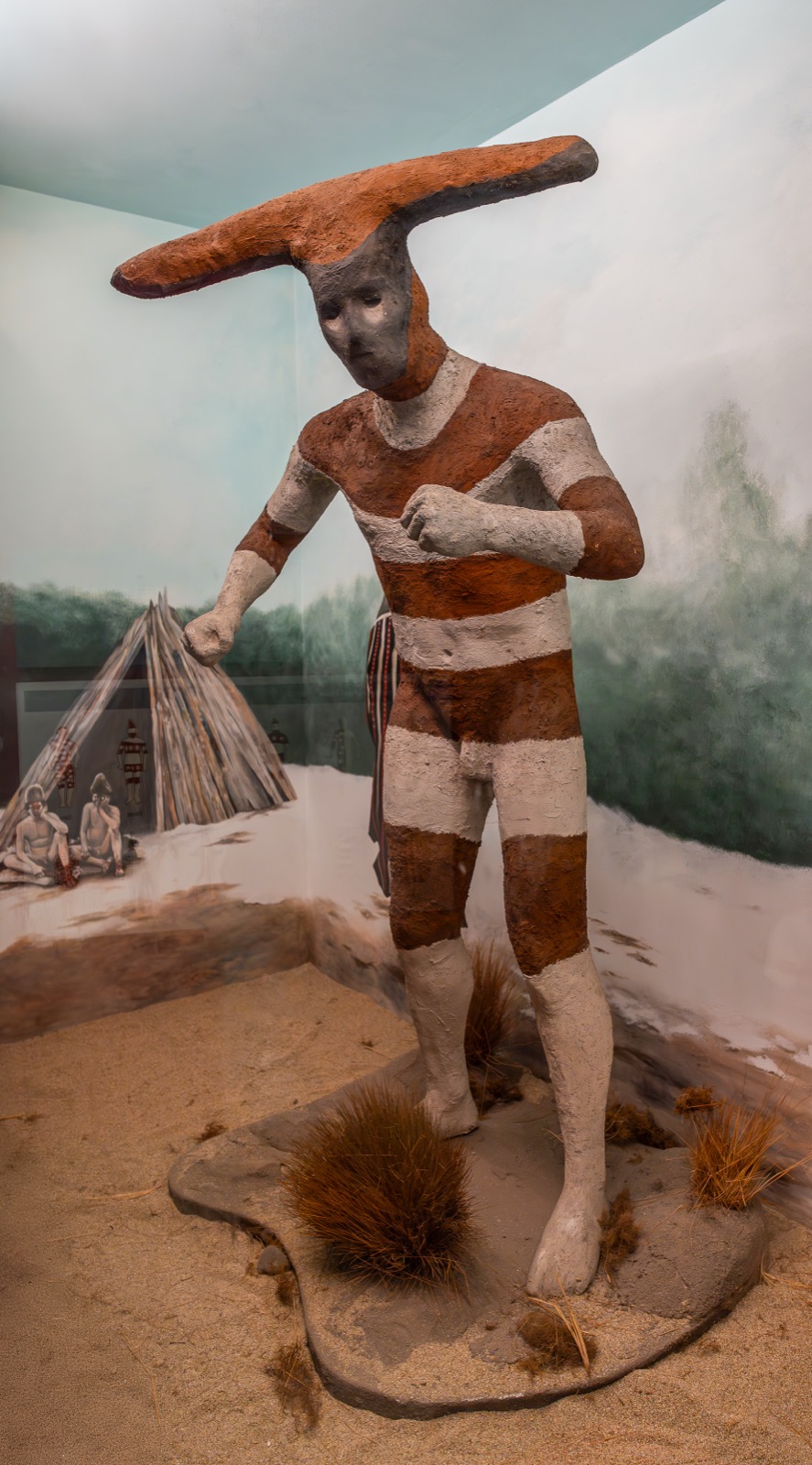 Life-size museum figure of a painted, horned Selk'nam Hain spirit with red and white body paint
